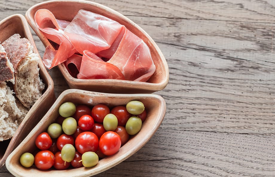 Jamon with appetizers on the wooden background